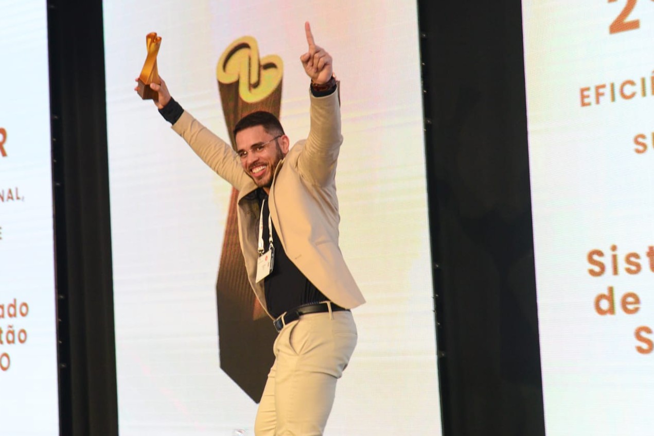 Luiz Arão Araújo Carvalho ergue o troféu no palco ao receber o Prêmio Inovação Tecnológica Condege, 1º lugar no CNTI.Def 2025